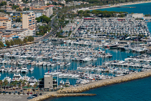 Aerial view of Port Vauban in Antibes filled with numerous yachts and boats bordered by stone breakwaters and the coastal urban landscape of Antibes Provence Alpes Cote d Azur France. Aerial view of Port Vauban in Antibes filled with numerous yachts and boats bordered by stone breakwaters and the coastal urban landscape of Antibes Provence Alpes Cote d Azur France.