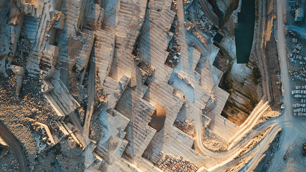 Aerial view of the Jadrankamen stone quarry with its terraced white limestone walls and geometric patterns under warm sunlight in Pucisca Splitsko dalmatinska Croatia. Aerial view of the Jadrankamen stone quarry with its terraced white limestone walls and geometric patterns under warm sunlight in Pucisca Splitsko dalmatinska Croatia.