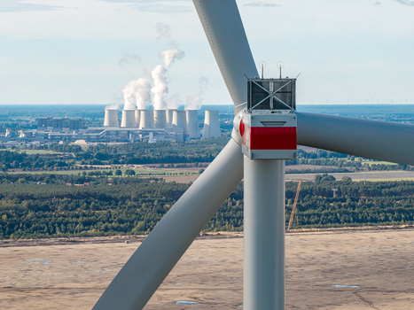 Aerial view of a wind turbine at Windpark Forst Briesnig II with the Janschwalde Power Plant emitting steam in the background situated on recultivated land in Forst Brandenburg Germany. Aerial view of a wind turbine at Windpark Forst Briesnig II with the Janschwalde Power Plant emitting steam in the background situated on recultivated land in Forst Brandenburg Germany.