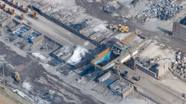 Aerial view of the Tata Steel industrial complex featuring heavy machinery gantry cranes and steam rising from processing areas Velsen Noord Noord Holland Netherlands. Aerial view of the Tata Steel industrial complex featuring heavy machinery gantry cranes and steam rising from processing areas Velsen Noord Noord Holland Netherlands.