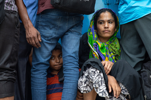 Dhaka Bangladesh 15 June 2018 View of a woman sitting on the floor and a young boy peeking through a crowd of people at the Airport Railway Station. Dhaka Bangladesh 15 June 2018 View of a woman sitting on the floor and a young boy peeking through a crowd of people at the Airport Railway Station.
