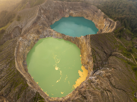 Aerial view of the Kelimutu National Park crater lakes with vibrant turquoise and green volcanic water surrounded by rugged rocky terrain in Detusoko East Nusa Tenggara Indonesia.