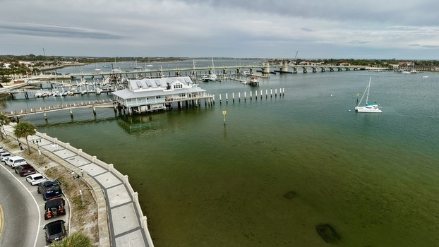Aerial view of the Bridge of Lions spanning the Matanzas River with boats docked near the historic waterfront and a white building on stilts in St. Augustine Florida United States.