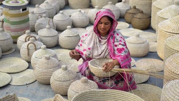 View of a woman weaving traditional baskets in Bogura Bangladesh. View of a woman weaving traditional baskets in Bogura Bangladesh.