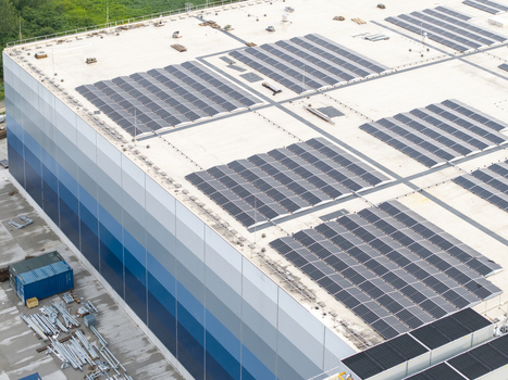 Aerial view of a modern logistics hub featuring extensive solar panel arrays on the roof and a blue gradient facade in Skawina Lesser Poland Voivode Poland. Aerial view of a modern logistics hub featuring extensive solar panel arrays on the roof and a blue gradient facade in Skawina Lesser Poland Voivode Poland.