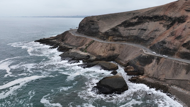 Aerial view of the coastal road winding along the cliffs of Barranco with waves crashing against the rocky shore in Barranco Lima Province Peru.