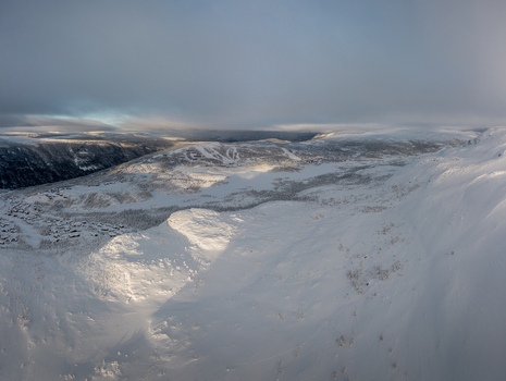 Aerial view of the snow covered landscape surrounding Gaustablikk Fjellresort with ski slopes and mountain peaks under a soft winter sky in Rjukan Telemark Norway. Aerial view of the snow covered landscape surrounding Gaustablikk Fjellresort with ski slopes and mountain peaks under a soft winter sky in Rjukan Telemark Norway.