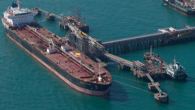 Aerial view of a large oil tanker docked at an industrial offshore terminal with complex piping systems and turquoise water Hong Kong Hong Kong. Aerial view of a large oil tanker docked at an industrial offshore terminal with complex piping systems and turquoise water Hong Kong Hong Kong.