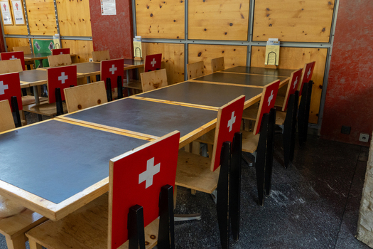 View of the interior of a traditional restaurant featuring wooden tables and chairs decorated with the Swiss flag in Gruyeres Fribourg Switzerland. View of the interior of a traditional restaurant featuring wooden tables and chairs decorated with the Swiss flag in Gruyeres Fribourg Switzerland.