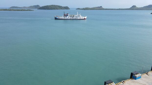 Bakauheni Indonesia 15 December 2021 Aerial view of a ferry boat crossing calm blue waters near the coast with lush green islands visible in the distance under a clear sky.