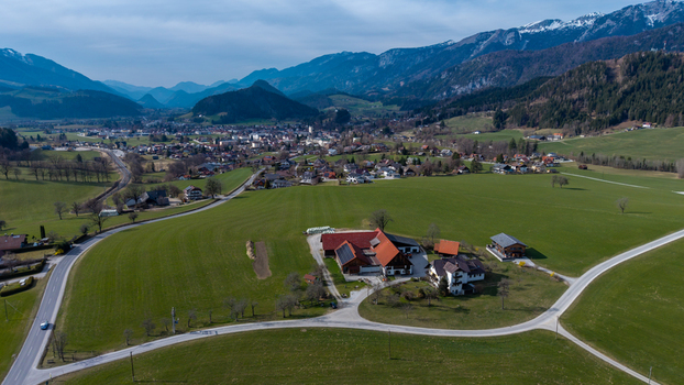 Aerial view of emerald fields unfurl towards the village nestled in the valley framed by majestic mountains Windischgarsten Upper Austria Austria. Aerial view of emerald fields unfurl towards the village nestled in the valley framed by majestic mountains Windischgarsten Upper Austria Austria.