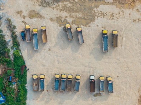 Aerial view of a construction area with rows of yellow dump trucks parked on a dirt ground in Bukit Tambun Penang Malaysia. Aerial view of a construction area with rows of yellow dump trucks parked on a dirt ground in Bukit Tambun Penang Malaysia.