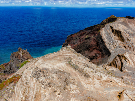 Aerial view of the volcanic landscape where the dark cliffs dramatically meet the deep blue sea Capelo A&ccedil;ores Portugal.