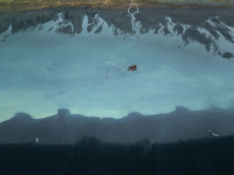 Aerial view of a shipwreck resting on the dark volcanic black sand beach with turquoise water in Iceland. Aerial view of a shipwreck resting on the dark volcanic black sand beach with turquoise water in Iceland.
