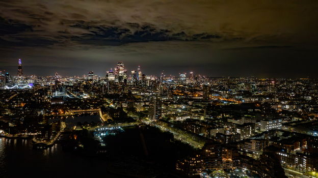 Aerial view of the illuminated London skyline at night featuring the Shard and modern skyscrapers glowing against the dark sky with the River Thames in London England United Kingdom.