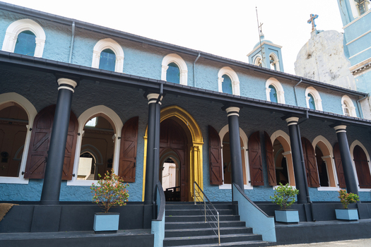 View of the historic St. Mary s Cathedral featuring blue walls black columns and arched windows with wooden shutters in Galle Southern Province Sri Lanka.