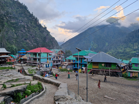 View of the historic village of Malana with colorful houses traditional architecture and people walking through the mountain valley in Malana Himachal Pradesh India.