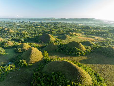 Aerial view of the Chocolate Hills a unique geological formation of grass covered conical mounds in the lush landscape of Batuan Central Visayas Philippines. Aerial view of the Chocolate Hills a unique geological formation of grass covered conical mounds in the lush landscape of Batuan Central Visayas Philippines.
