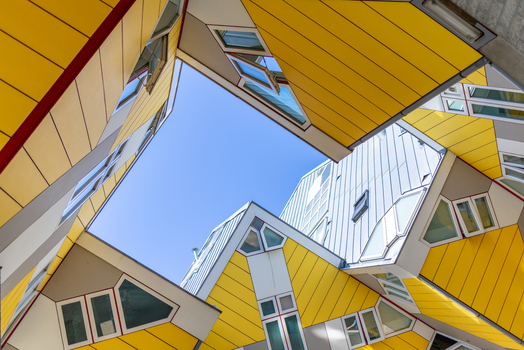 View of the iconic yellow Cube Houses with their unique geometric architecture under a clear blue sky in Rotterdam South Holland Netherlands. View of the iconic yellow Cube Houses with their unique geometric architecture under a clear blue sky in Rotterdam South Holland Netherlands.