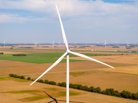 Aerial view of wind turbines in a vast agricultural field under a clear blue sky in Wolcott Indiana United States.