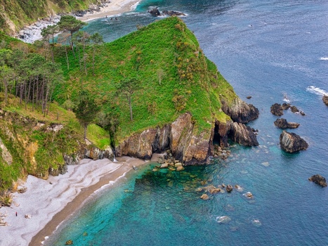 Aerial view of Silence Beach Viewpoint with rugged green cliffs turquoise ocean water and a pebble shore in Cudillero Asturias Spain.