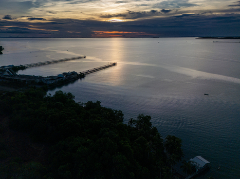 Aerial view of Bintan Island coastline with long wooden piers extending into the calm sea during a golden sunset in Tanjung Pinang Riau Islands Indonesia. Aerial view of Bintan Island coastline with long wooden piers extending into the calm sea during a golden sunset in Tanjung Pinang Riau Islands Indonesia.