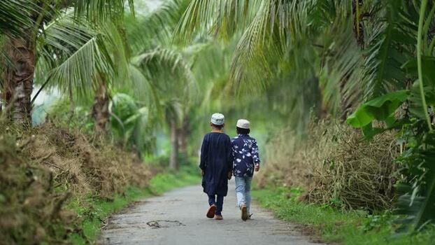 View of two boys walking on a path through palm trees Bangladesh. View of two boys walking on a path through palm trees Bangladesh.
