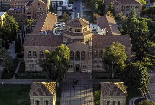 Aerial view of Royce Hall at UCLA Campus featuring Romanesque Revival architecture red tiled roofs and surrounding trees in golden hour light in Westwood California United States.