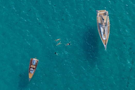 Aerial view of Ile Sainte Marguerite with two boats anchored in turquoise water and people swimming in the sea near Cannes Provence Alpes Cote d Azur France. Aerial view of Ile Sainte Marguerite with two boats anchored in turquoise water and people swimming in the sea near Cannes Provence Alpes Cote d Azur France.