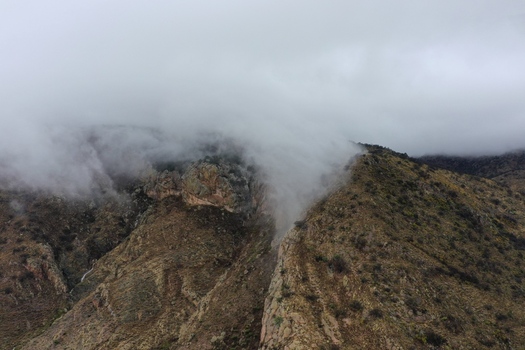 Aerial view of the rugged Sierra de San Miguelito mountain range partially shrouded in thick low hanging clouds and mist in San Luis Potosi San Luis Potosi Mexico. Aerial view of the rugged Sierra de San Miguelito mountain range partially shrouded in thick low hanging clouds and mist in San Luis Potosi San Luis Potosi Mexico.