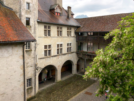Gruyeres Switzerland 14 May 2026 View of Gruyeres Castle courtyard with stone arches wooden balconies and a flowering tree under a cloudy sky. Gruyeres Switzerland 14 May 2026 View of Gruyeres Castle courtyard with stone arches wooden balconies and a flowering tree under a cloudy sky.