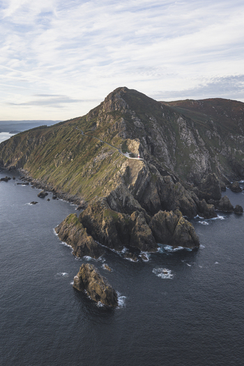 Aerial view of a lighthouse perched on a rugged cliffside overlooking the Atlantic Ocean in Galicia Spain.