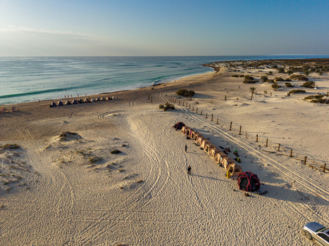 Aerial view of tents lined up on the sandy beach with the turquoise sea meeting the shore in the distance Kadrihnitin Socotra Yemen. Aerial view of tents lined up on the sandy beach with the turquoise sea meeting the shore in the distance Kadrihnitin Socotra Yemen.