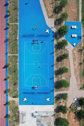 Aerial view of a vibrant blue basketball court and a red running track surrounded by green trees in Turin Piedmont Italy. Aerial view of a vibrant blue basketball court and a red running track surrounded by green trees in Turin Piedmont Italy.