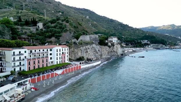 Aerial view of a coastal hotel and rocky cliffs in Taormina Italy.