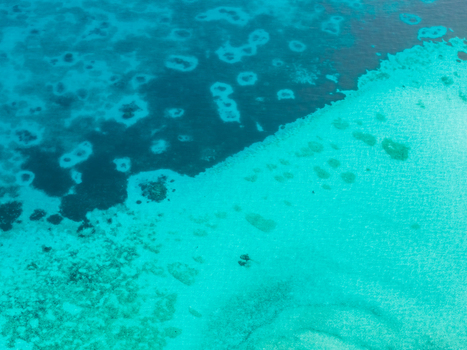 Aerial view of the tranquil turquoise waters gently caressing the pristine shores of Kan island a symphony of blues and greens Dhidhdhoo Maldives.