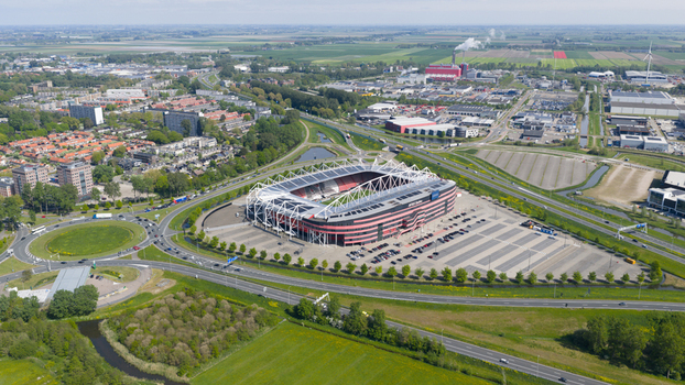 Alkmaar Netherlands 05 May 2026 Aerial view of AFAS stadium featuring its modern architecture large parking lot and surrounding industrial landscape under a clear sky.