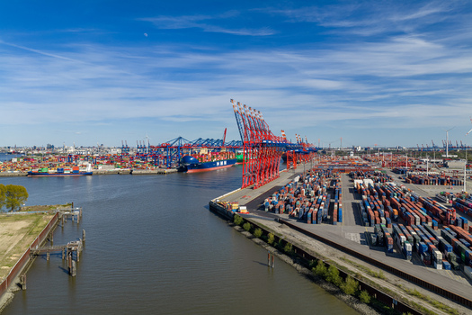 Aerial view of Waltershofer Hafen with red gantry cranes and rows of colorful shipping containers under a blue sky in Hamburg Hamburg Germany. Aerial view of Waltershofer Hafen with red gantry cranes and rows of colorful shipping containers under a blue sky in Hamburg Hamburg Germany.
