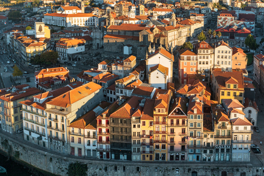Aerial view of the historic city of Porto with its iconic terracotta rooftops narrow streets and traditional architecture in warm golden hour light in Porto Porto District Portugal.