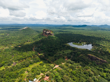 Aerial view of Sigiriya Lion Rock fortress surrounded by dense tropical jungle and a calm lake under a cloudy sky in Sigiriya Central Province Sri Lanka. Aerial view of Sigiriya Lion Rock fortress surrounded by dense tropical jungle and a calm lake under a cloudy sky in Sigiriya Central Province Sri Lanka.