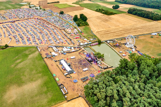Herzogenaurach Germany 22 July 2022 Aerial view of the Open Beatz Festival featuring stages a ferris wheel and crowds surrounded by agricultural fields and camping areas. Herzogenaurach Germany 22 July 2022 Aerial view of the Open Beatz Festival featuring stages a ferris wheel and crowds surrounded by agricultural fields and camping areas.