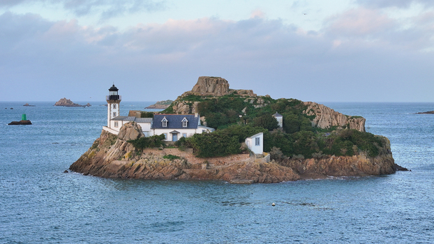 Aerial view of Louet island featuring the historic lighthouse and keeper s house surrounded by the blue waters of Morlaix Bay Carantec Brittany France. Aerial view of Louet island featuring the historic lighthouse and keeper s house surrounded by the blue waters of Morlaix Bay Carantec Brittany France.