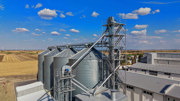 Aerial view of the storage silo Bavaniste with metallic grain bins industrial structures and surrounding agricultural fields under a blue sky in Bavaniste Vojvodina Serbia.