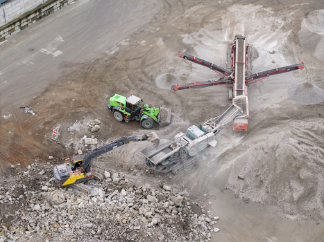 Aerial view of heavy machinery including an excavator and a wheel loader operating at a demolition site with piles of rubble and gravel in Krakow Lesser Poland Voivode Poland.