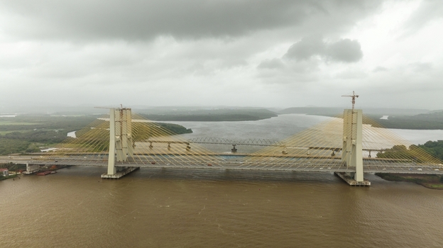 Aerial view of the Zuari Bridge spanning the river with its cable stayed design construction cranes and cloudy sky in the background in Cortalim Goa India.