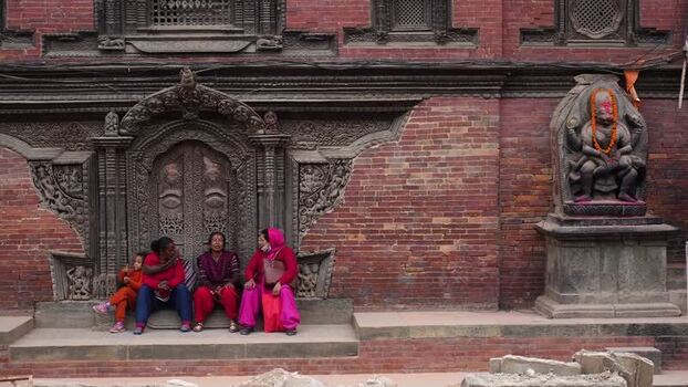 View of people sitting by a carved door in Kathmandu Nepal.