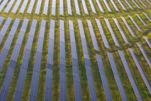 Aerial view of a large solar farm with rows of photovoltaic panels installed on a green field in Poland.
