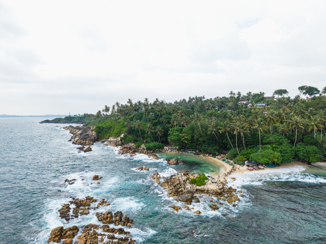 Aerial view of Secret Beach Mirissa featuring a rocky coastline turquoise waters and lush palm trees along the sandy shore in Mirissa Southern Province Sri Lanka. Aerial view of Secret Beach Mirissa featuring a rocky coastline turquoise waters and lush palm trees along the sandy shore in Mirissa Southern Province Sri Lanka.