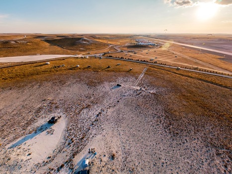 Aerial view of the arid landscape near Sivrihisar with paragliders in the sky during golden hour featuring dry terrain a road and parked vehicles in Sivrihisar Eskisehir Turkey. Aerial view of the arid landscape near Sivrihisar with paragliders in the sky during golden hour featuring dry terrain a road and parked vehicles in Sivrihisar Eskisehir Turkey.