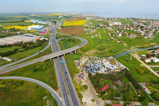 Aerial view of a highway interchange surrounded by green fields industrial buildings and residential areas near the coast in Silivri Istanbul Turkey. Aerial view of a highway interchange surrounded by green fields industrial buildings and residential areas near the coast in Silivri Istanbul Turkey.